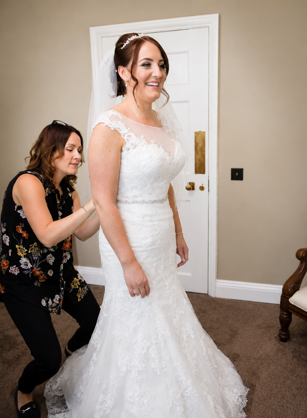 A bride at her final fitting at the Acula studio, the seamstress crouched adjusting the hem